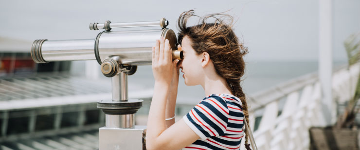 Menina utilizando um binóculos fixo